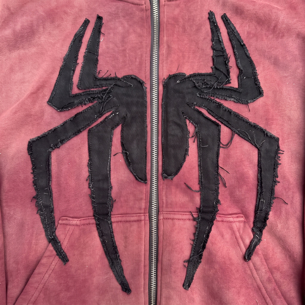 Close-up of the hand-sewn raw-edge black spider applique across the chest