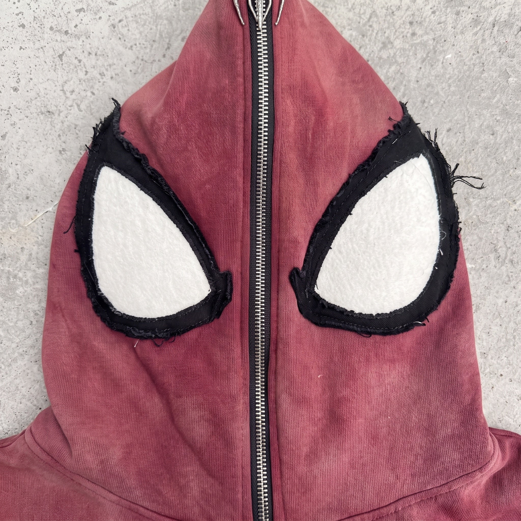 Close-up of the hand-sewn white raw-edge eye appliques on the hood