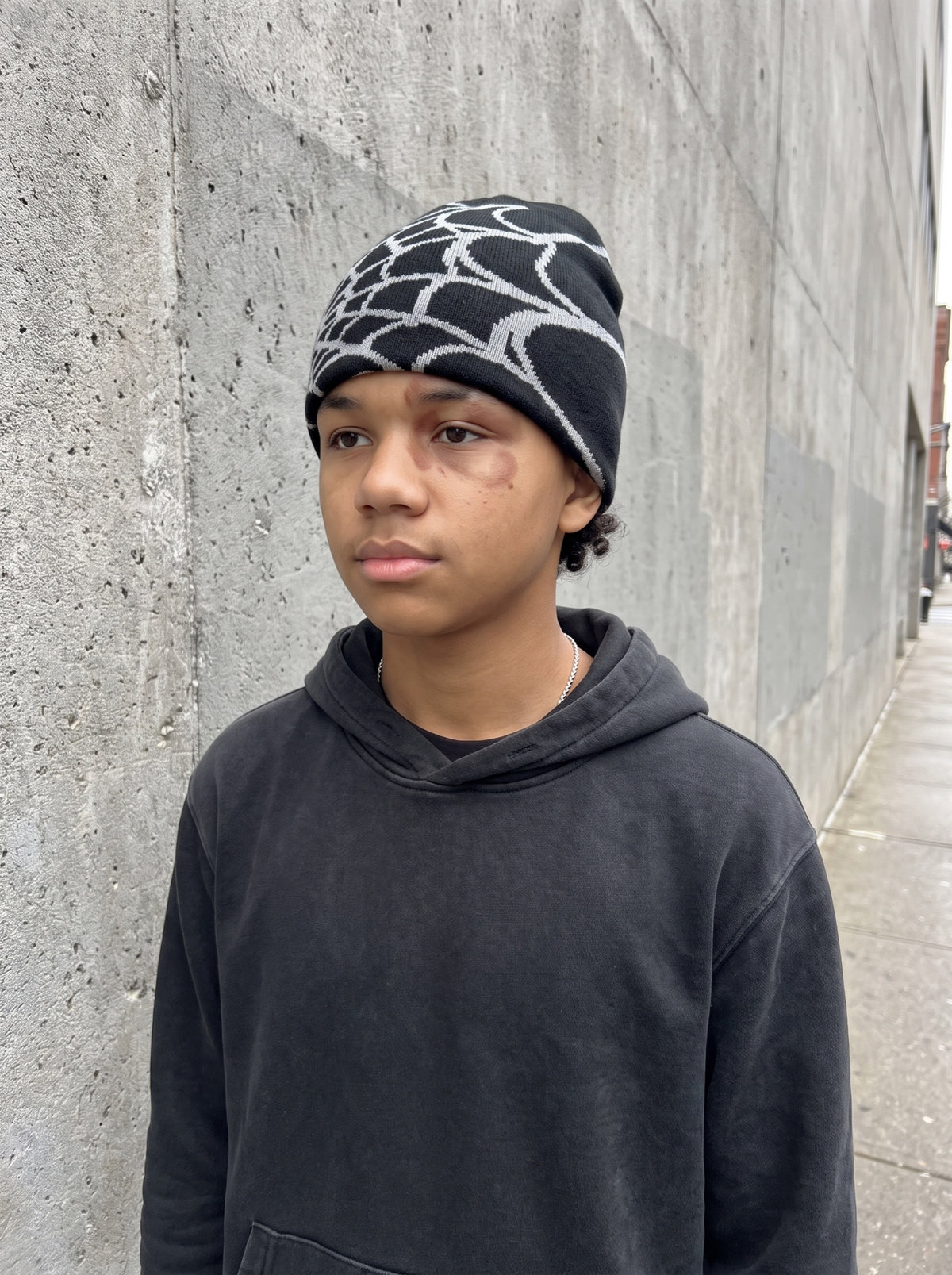 Black and ash web knit beanie worn on the street, front view