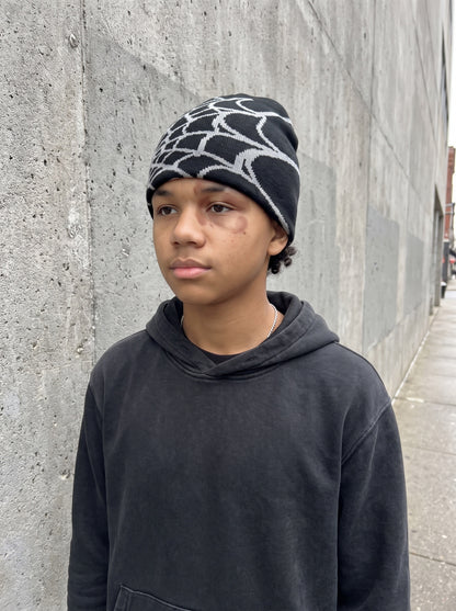 Black and ash web knit beanie worn on the street, front view