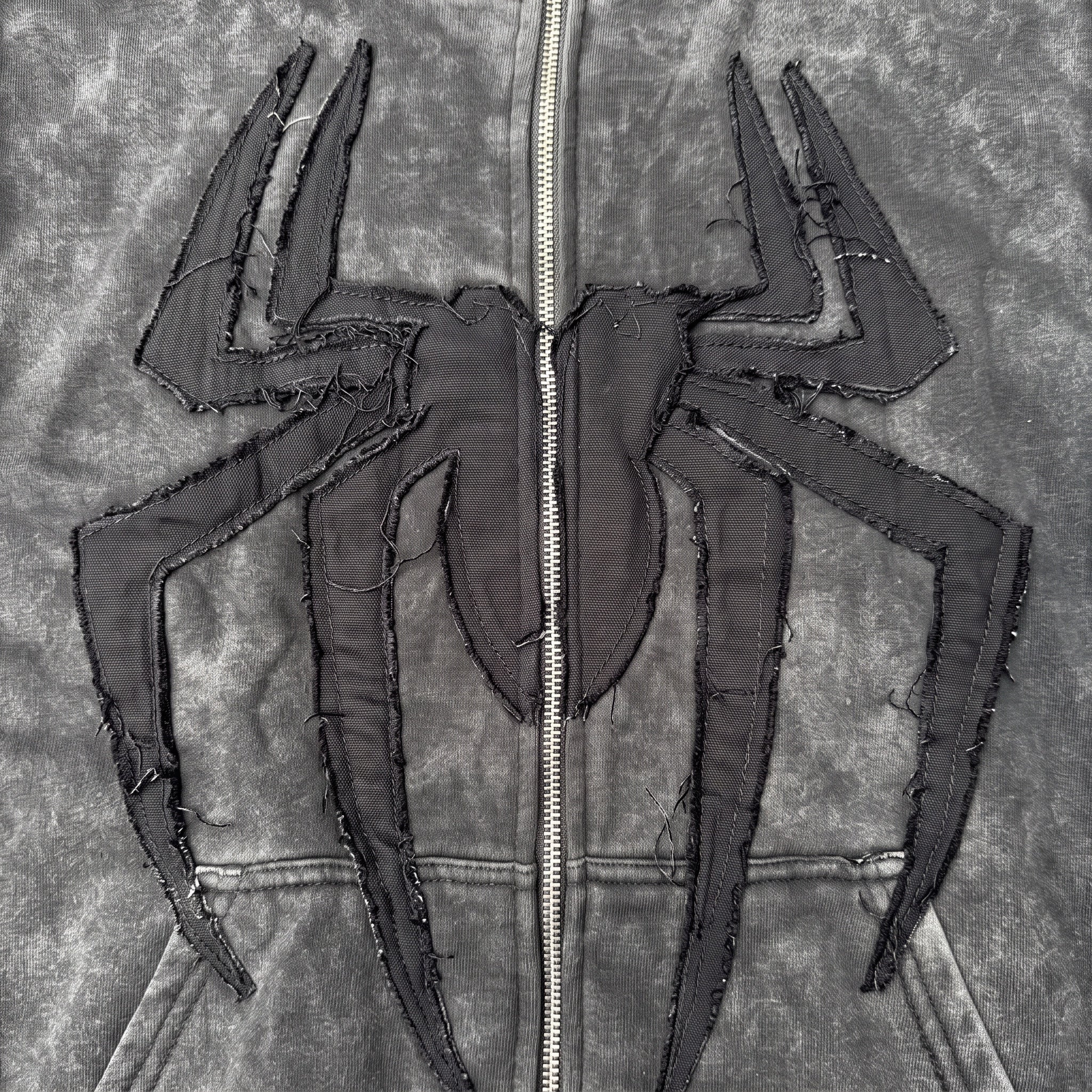 Close-up of the tonal black raw-edge spider applique on the Washed Black hoodie