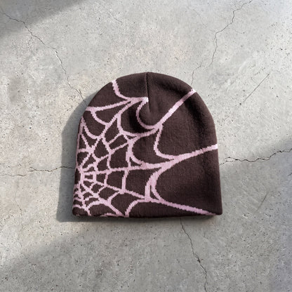 Cocoa brown web knit beanie with pink web on raw concrete
