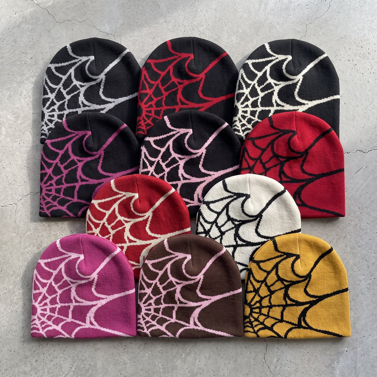 All eleven web knit beanie colourways laid out on concrete
